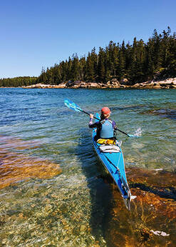 A solo kayaker paddles on a lake.