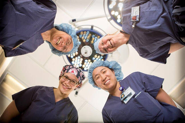 Four residents in operating room wearing scrub attire