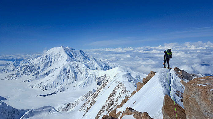 A hiker standing on a snowy mountaintop